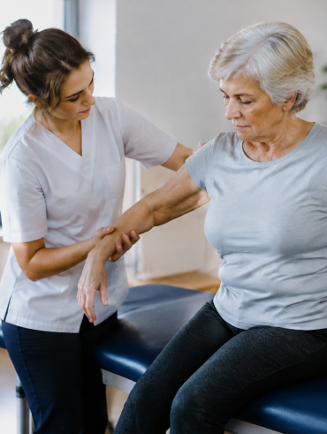Kinesitherapeute aide patient assis sur table de soins
